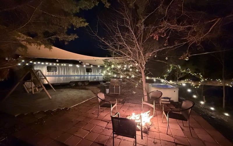 Airstream with fire pit and hot tub at night