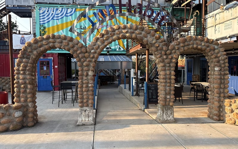 InnHabit cobblestone arch entrance with murals and string lights